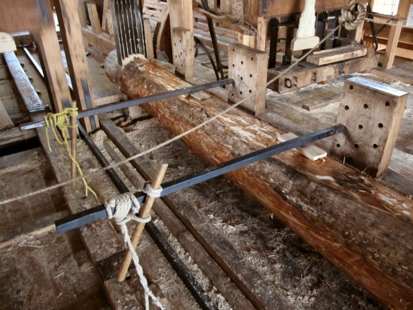 The log to be sawn is affixed to a wooden sled. Which each upward motion of the saw it is pushed 1 mm into the saw blades.